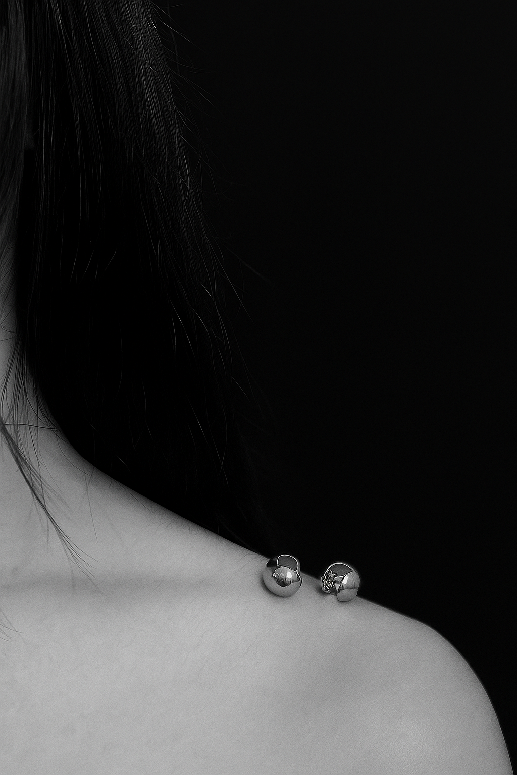 Close-up of a person wearing silver earrings against a black background